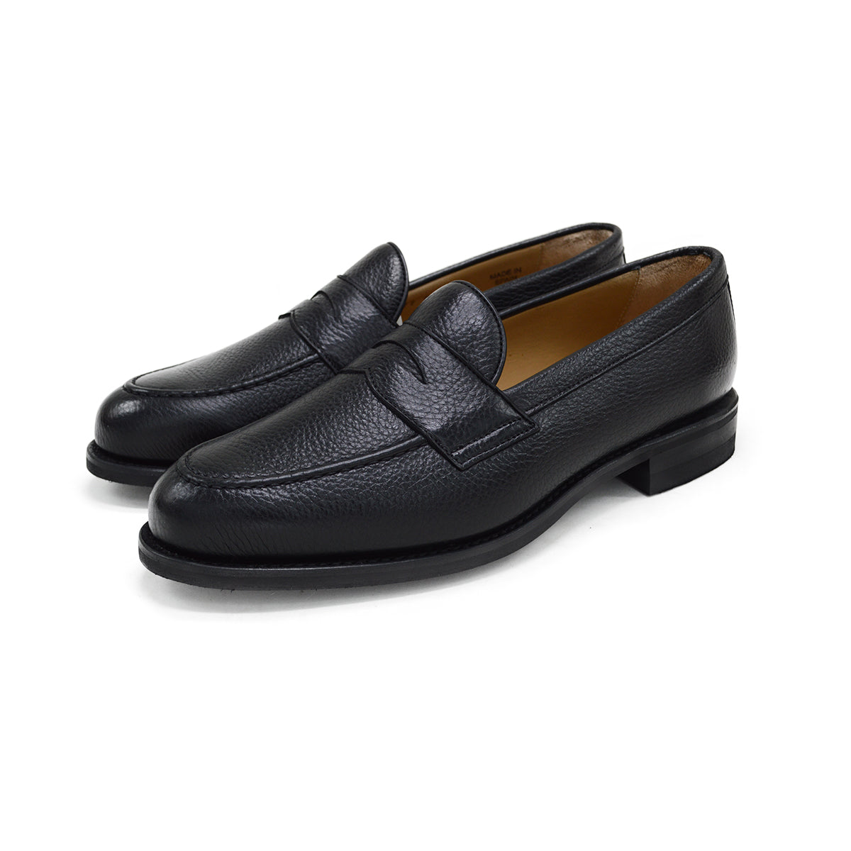 A black deerskin Penny loafer with a velvety soft texture and a classic round toe & Dainite sole, set against a white background.