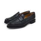 A black deerskin Penny loafer with a velvety soft texture and a classic round toe & Dainite sole, set against a white background.