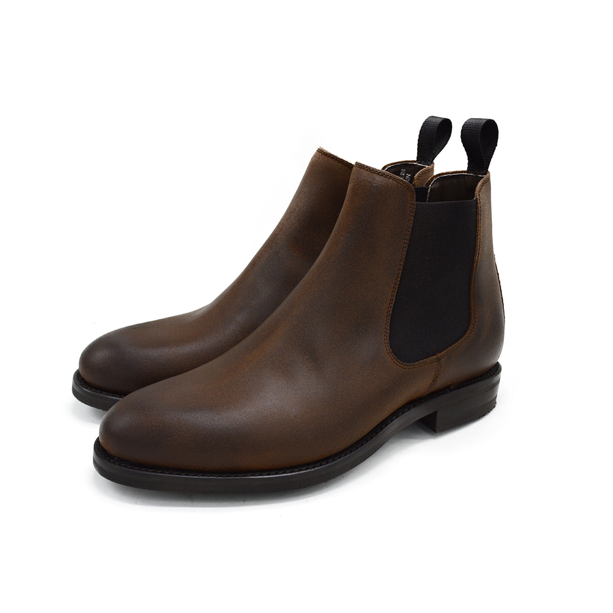 A dark brown Chelsea boot with a waxy leather finish and a contrasting black elastic side panel. The boot has a low heel and a small pull tab at the rear.