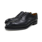 A Berwick 1707 black Oxford brogue shoe with brogue detailing and a lace-up closure. The shoe is made of smooth leather and appears to be sturdy and durable.