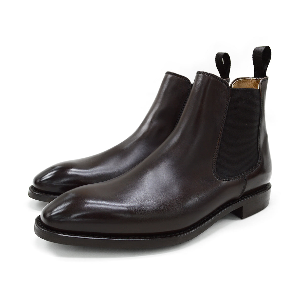 A dark brown leather Chelsea boot with a side pull tab and a low heel & Dainite soles, displayed on a white background.