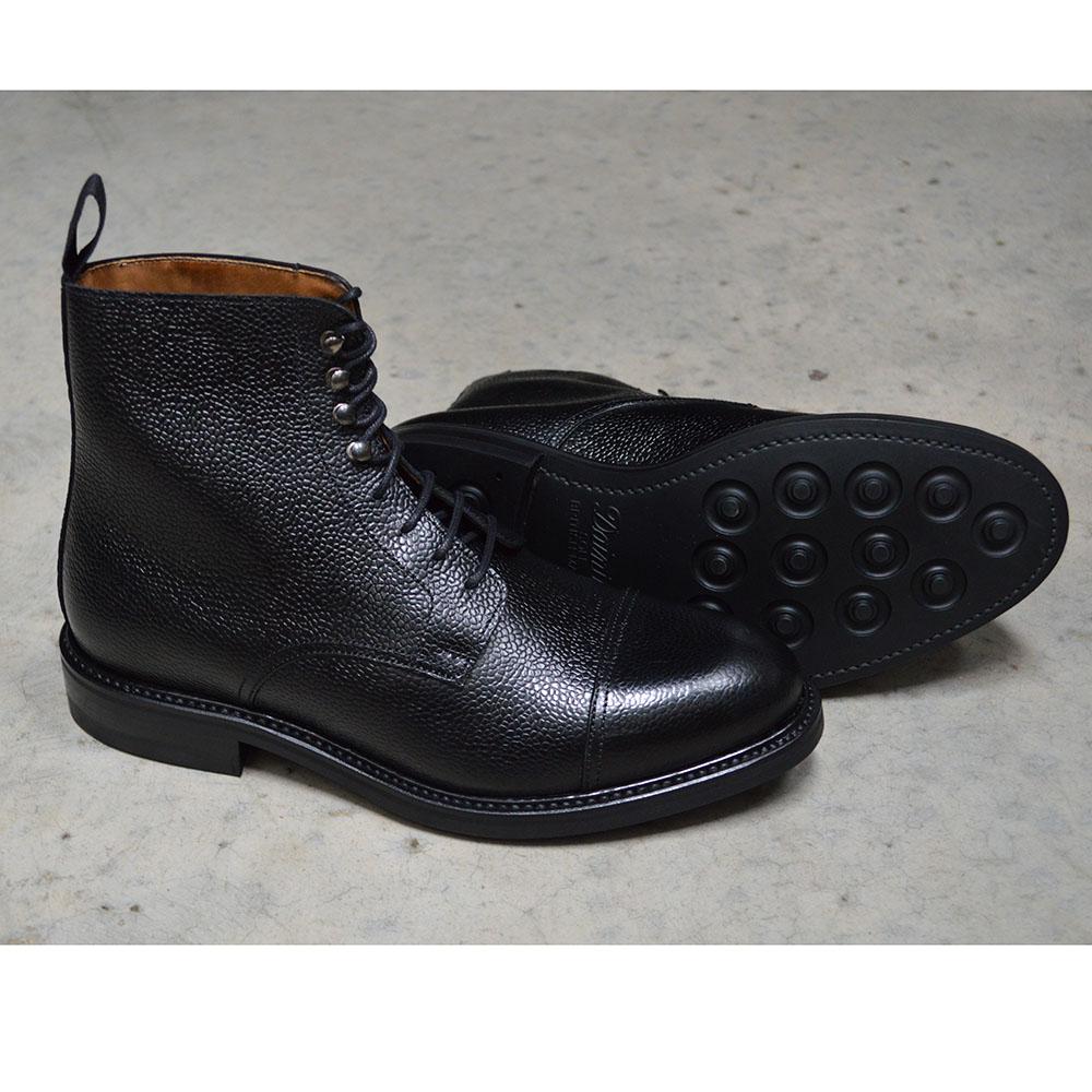 A Berwick 1707 black grain toe cap boot with a full lace-up construction and a round toe shape, set against a polished concrete background.
