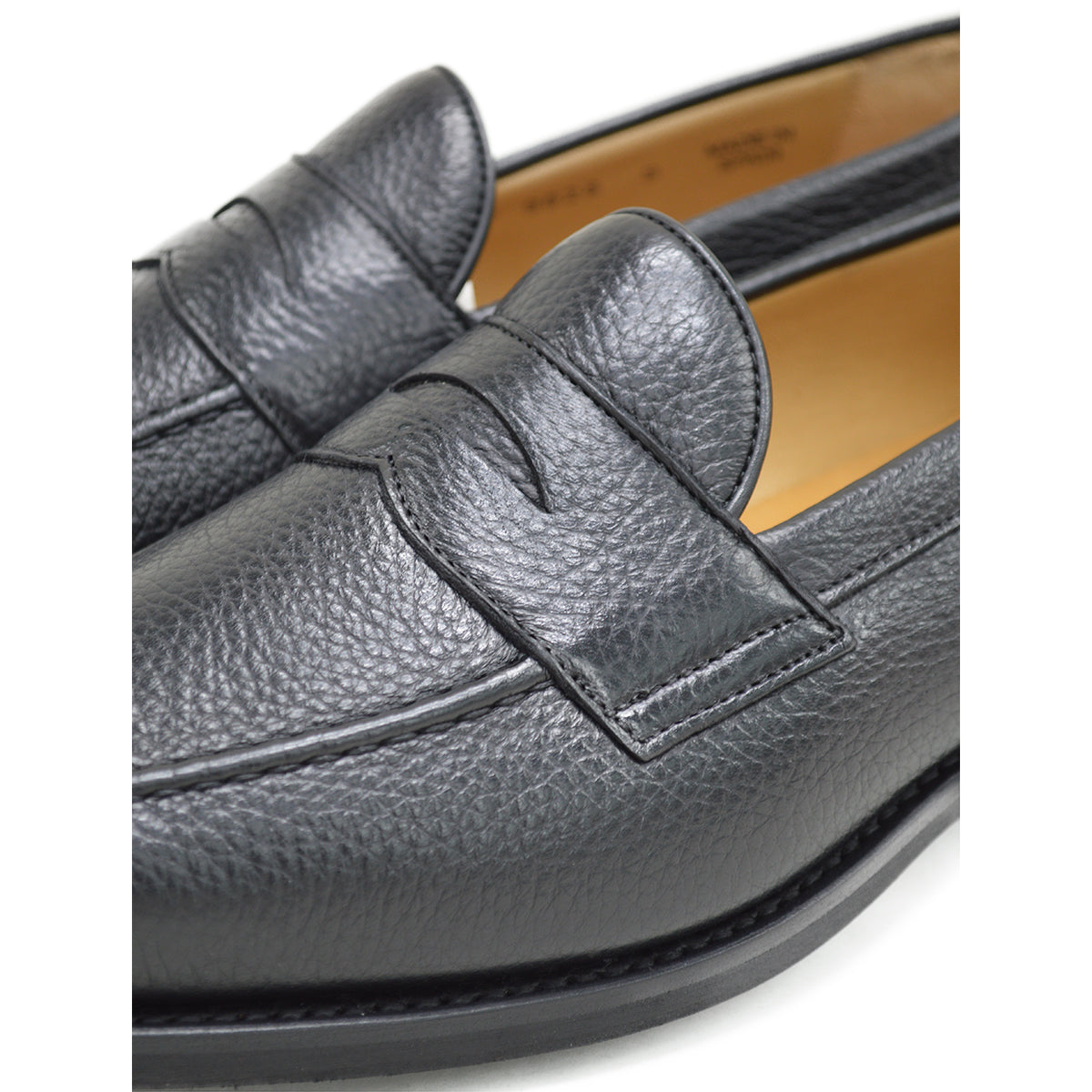 A black deerskin Penny loafer with a velvety soft texture and a classic round toe & Dainite sole, set against a white background.