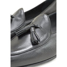 A black deerskin leather tassel Belgian loafer with an almond-shaped toe and a subtle tread sole, displayed against a white background.