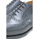 A Berwick 1707 black Oxford brogue shoe with brogue detailing and a lace-up closure. The shoe is made of smooth leather and appears to be sturdy and durable.