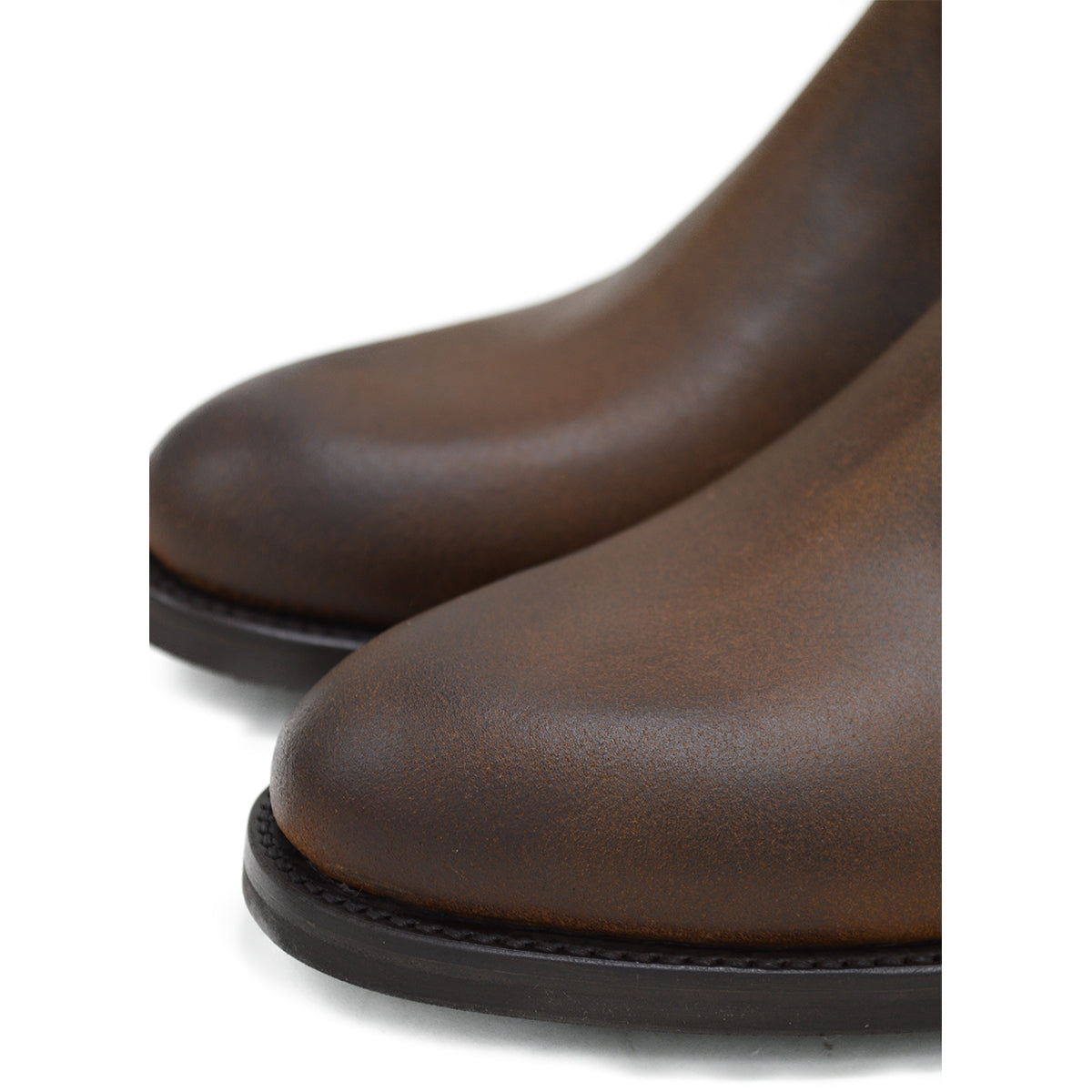 A dark brown Chelsea boot with a waxy leather finish and a contrasting black elastic side panel. The boot has a low heel and a small pull tab at the rear.
