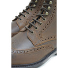 A dark brown lace-up brogue boot with a rubber sole and visible stitching on the upper part.