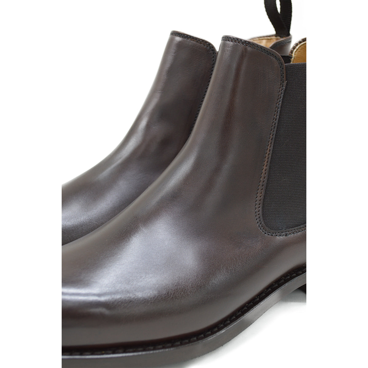 A dark brown leather Chelsea boot with a side pull tab and a low heel & Dainite soles, displayed on a white background.