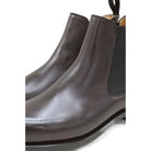 A dark brown leather Chelsea boot with a side pull tab and a low heel & Dainite soles, displayed on a white background.