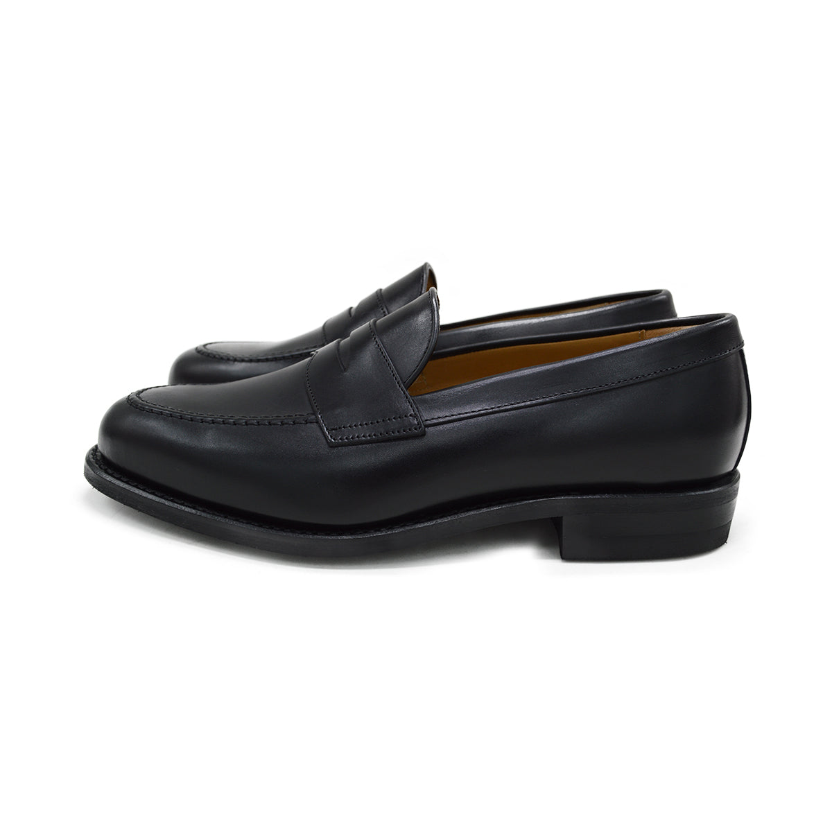 A black calf leather penny loafer with a Dainite rubber sole, showing a classic round toe shape and the iconic penny slot detail.