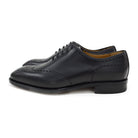 A black wholecut Oxford brogue shoe with a brogue pattern on the upper, a lace-up closure, and a goodyear welted leather sole.