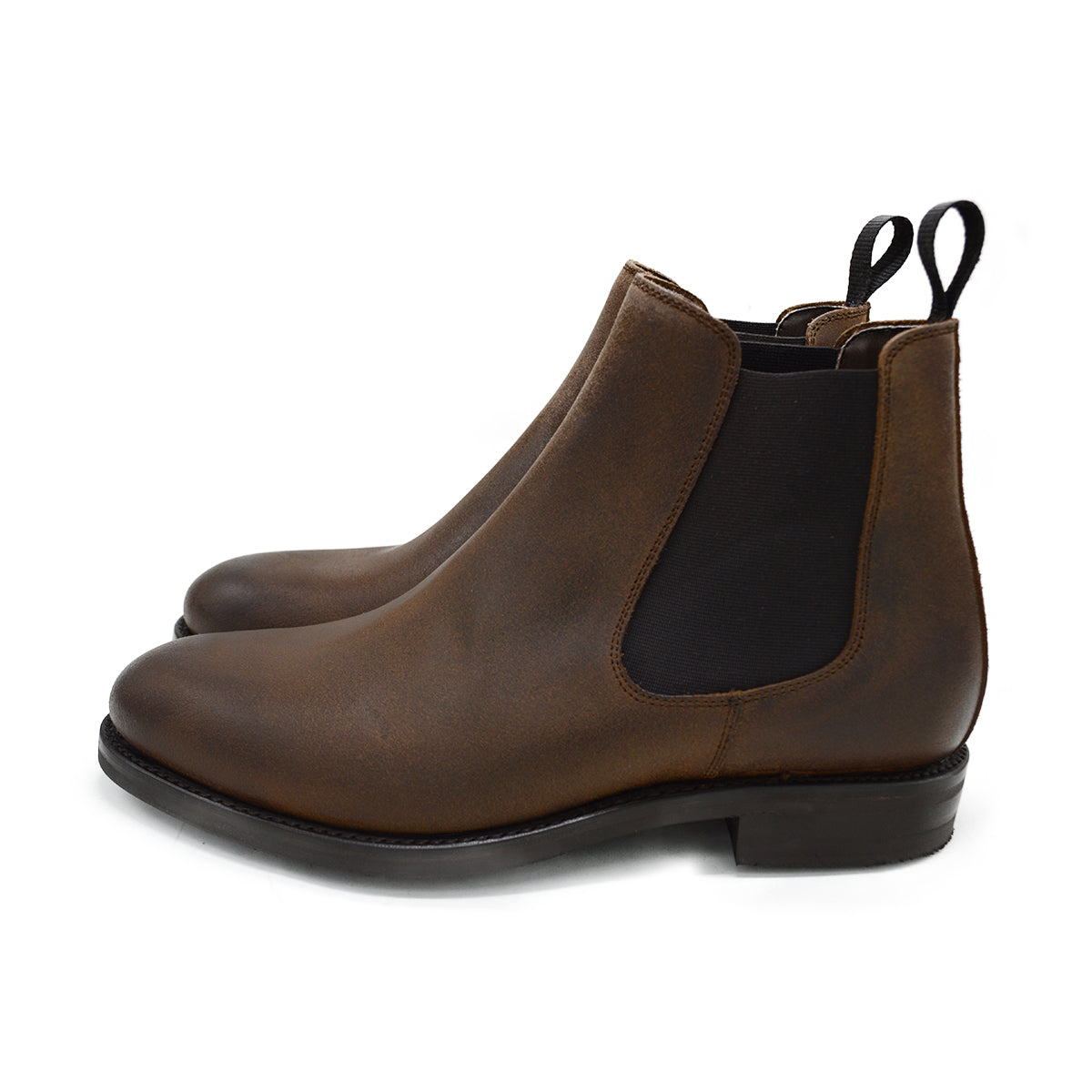 A dark brown Chelsea boot with a waxy leather finish and a contrasting black elastic side panel. The boot has a low heel and a small pull tab at the rear.