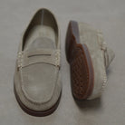 Pair of sand loafers with brown soles on a gray background
