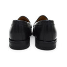 A black calf leather penny loafer with a Dainite rubber sole, showing a classic round toe shape and the iconic penny slot detail.