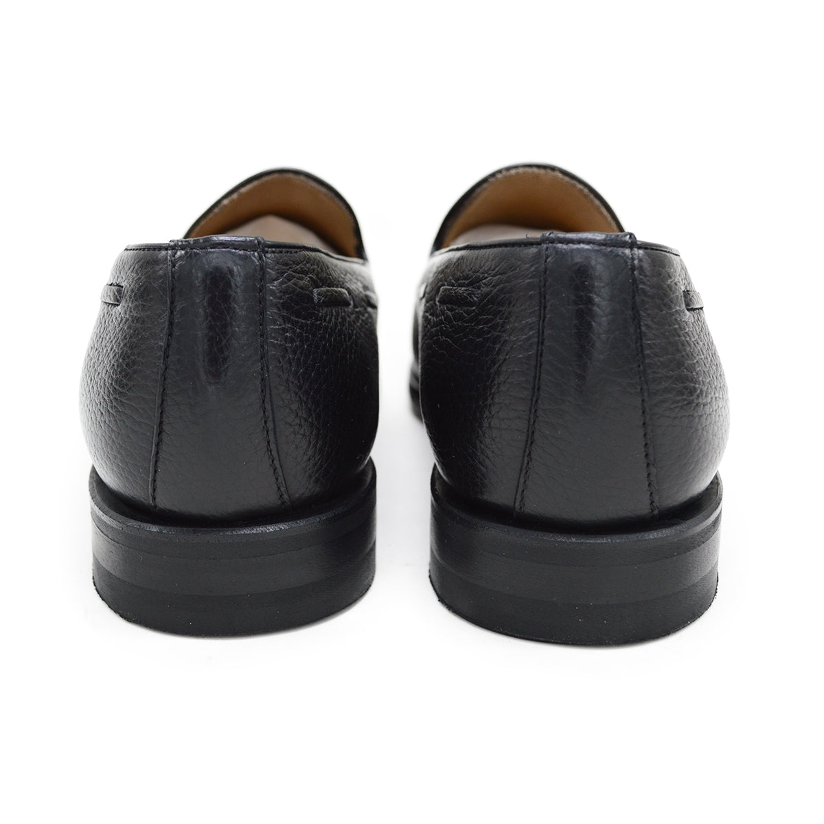 A black deerskin slip-on loafer with a tassel detail on the vamp, featuring a classic round toe and a low heel.