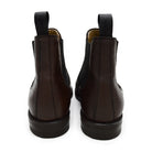 A dark brown grain leather Chelsea boot with a black elastic side panel and a round toe. The boot has a low heel and a goodyear welted dainite rubber sole.