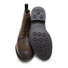 A dark brown lace-up brogue boot with a rubber sole and visible stitching on the upper part.