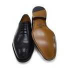A black wholecut Oxford brogue shoe with a brogue pattern on the upper, a lace-up closure, and a goodyear welted leather sole.