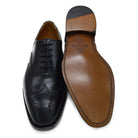 A Berwick 1707 black Oxford brogue shoe with brogue detailing and a lace-up closure. The shoe is made of smooth leather and appears to be sturdy and durable.