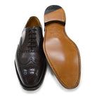 A Berwick 1707 brown Oxford brogue shoe with brogue detailing and a lace-up closure. The shoe is made of smooth leather and appears to be sturdy and durable.