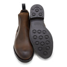 A dark brown Chelsea boot with a waxy leather finish and a contrasting black elastic side panel. The boot has a low heel and a small pull tab at the rear.