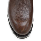 A dark brown grain leather Chelsea boot with a black elastic side panel and a round toe. The boot has a low heel and a goodyear welted dainite rubber sole.