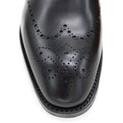 A black wholecut Oxford brogue shoe with a brogue pattern on the upper, a lace-up closure, and a goodyear welted leather sole.