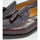 A Berwick 1707 burgundy hi shine leather slip-on shoe with a tassel detail on the vamp, set against a white background.
