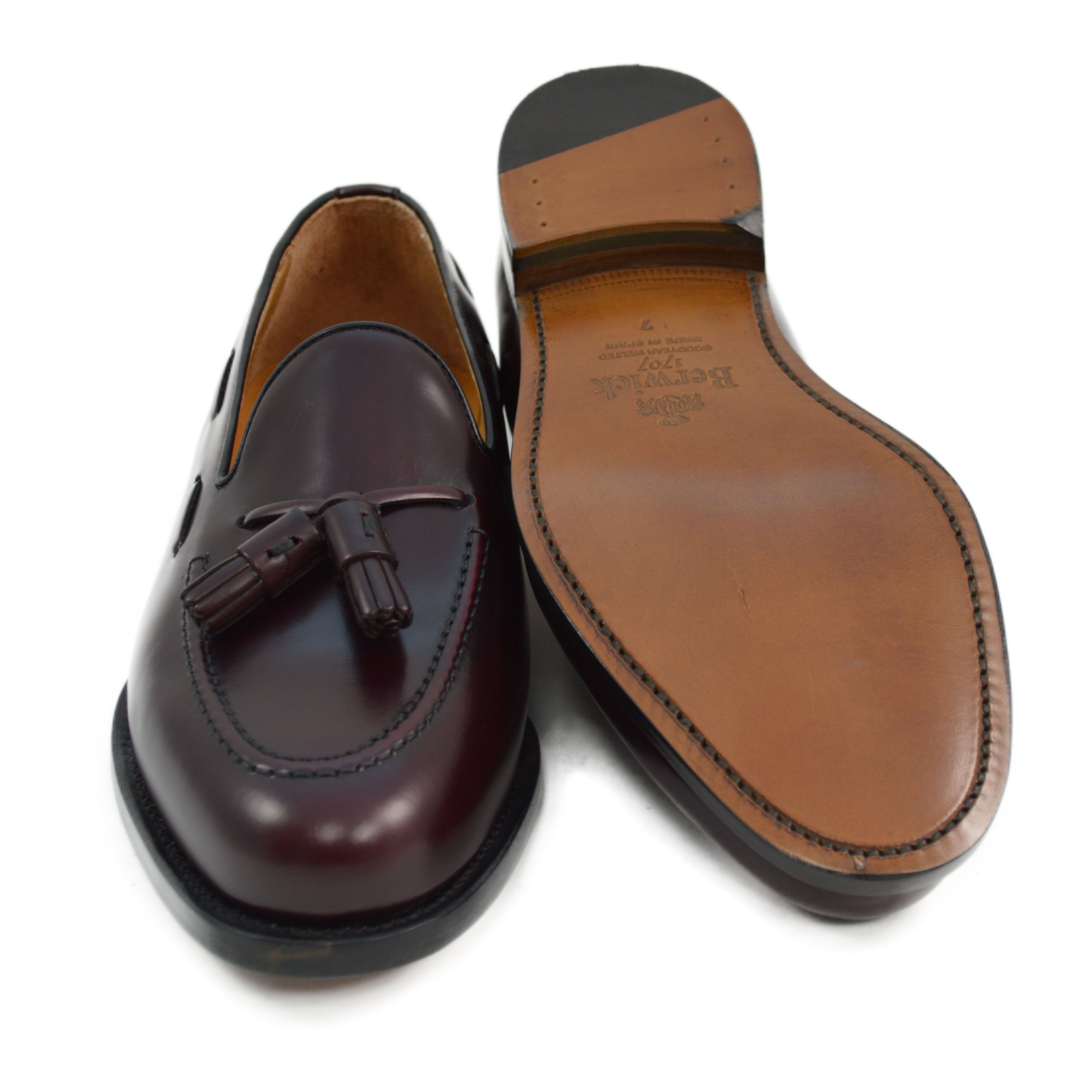 A Berwick 1707 burgundy hi shine leather slip-on shoe with a tassel detail on the vamp, set against a white background.