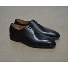 A black Berwick 1707 Wholecut Oxford shoe made from box calf leather with a lace-up closure and a round toe.