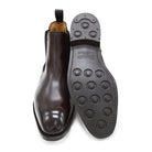 A dark brown leather Chelsea boot with a side pull tab and a low heel & Dainite soles, displayed on a white background.