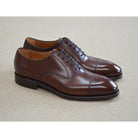 A Berwick 1707 dark brown, chisel toe Oxford shoe with a lace-up closure and a single leather sole.