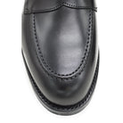 A black calf leather penny loafer with a Dainite rubber sole, showing a classic round toe shape and the iconic penny slot detail.