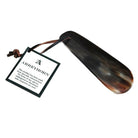 A flat-shaped shoe horn made of natural horn with a brown leather thong strap.