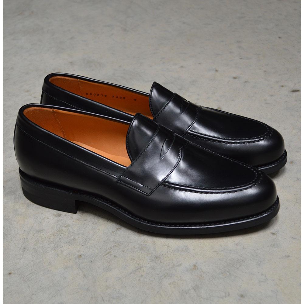 A black high-shine Berwick 1707 Penny Loafer with a round toe and Dainite rubber sole.