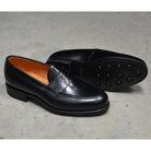 A black high-shine Berwick 1707 Penny Loafer with a round toe and Dainite rubber sole.