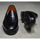 A black high-shine Berwick 1707 Penny Loafer with a round toe and Dainite rubber sole.