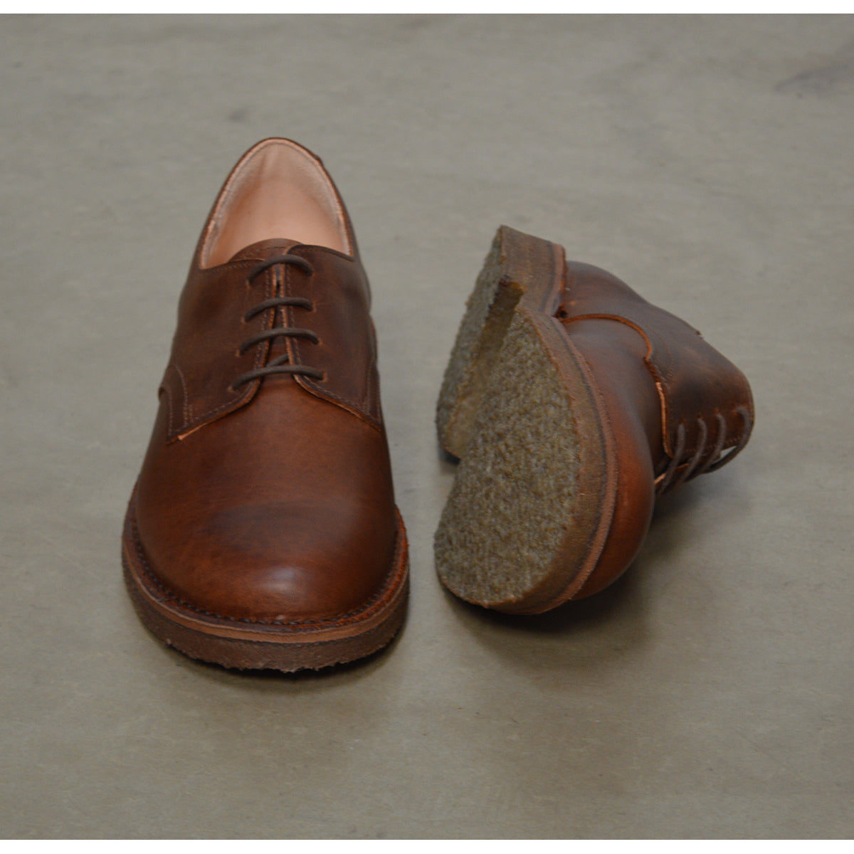 A dark chestnut brown Astorflex Redflex derby shoe made of nubuck leather, featuring a natural crepe rubber sole.