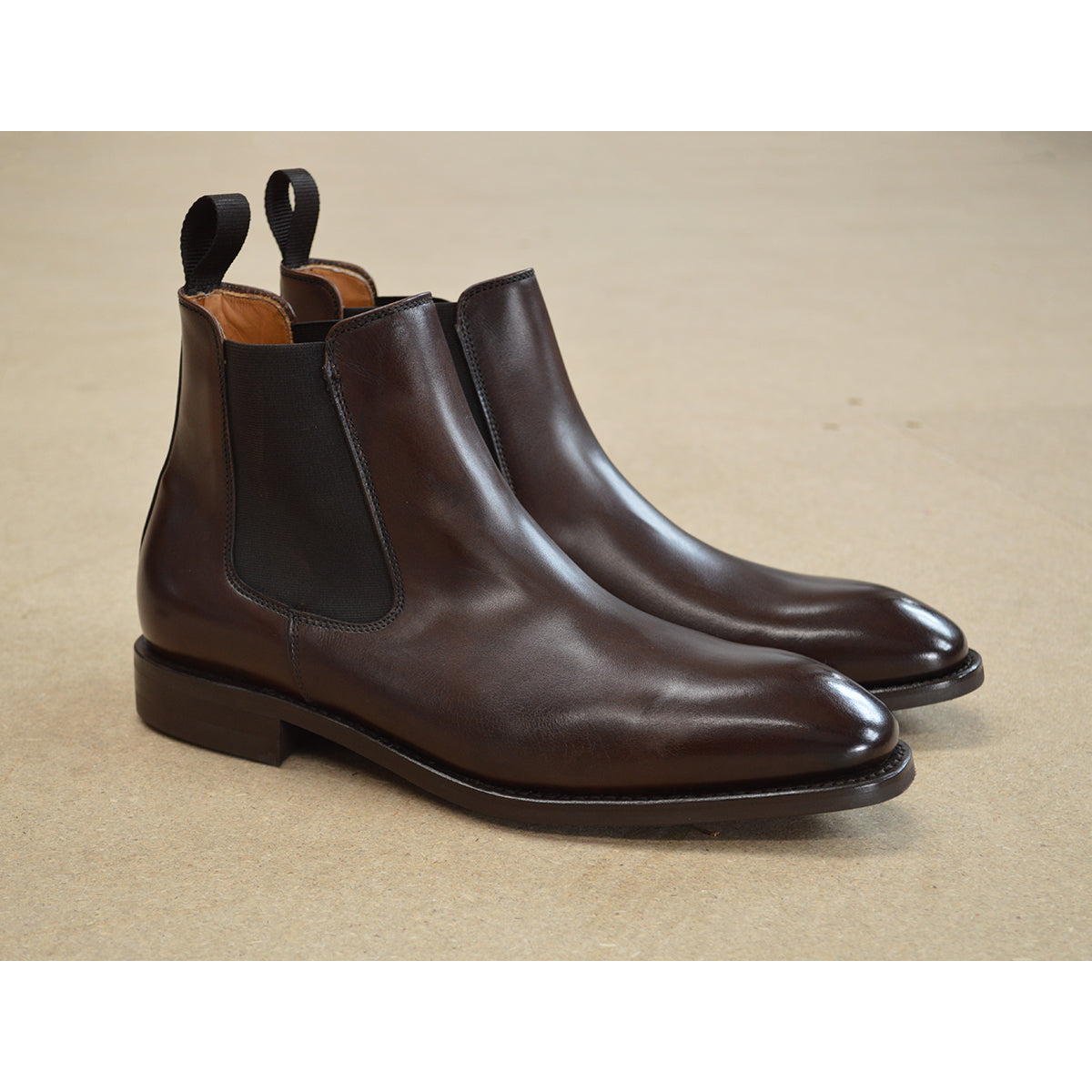 A dark brown leather Chelsea boot with a side pull tab and a low heel & Dainite soles