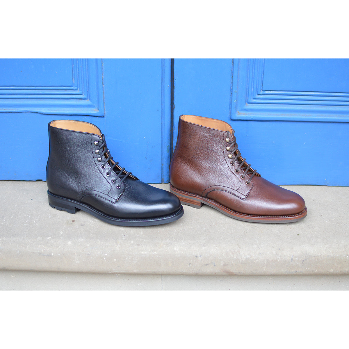 Black and brown leather boots on a stone surface with a blue door in the background