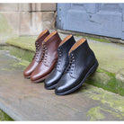 Pair of brown and black leather boots on a stone step with a wooden door in the background.