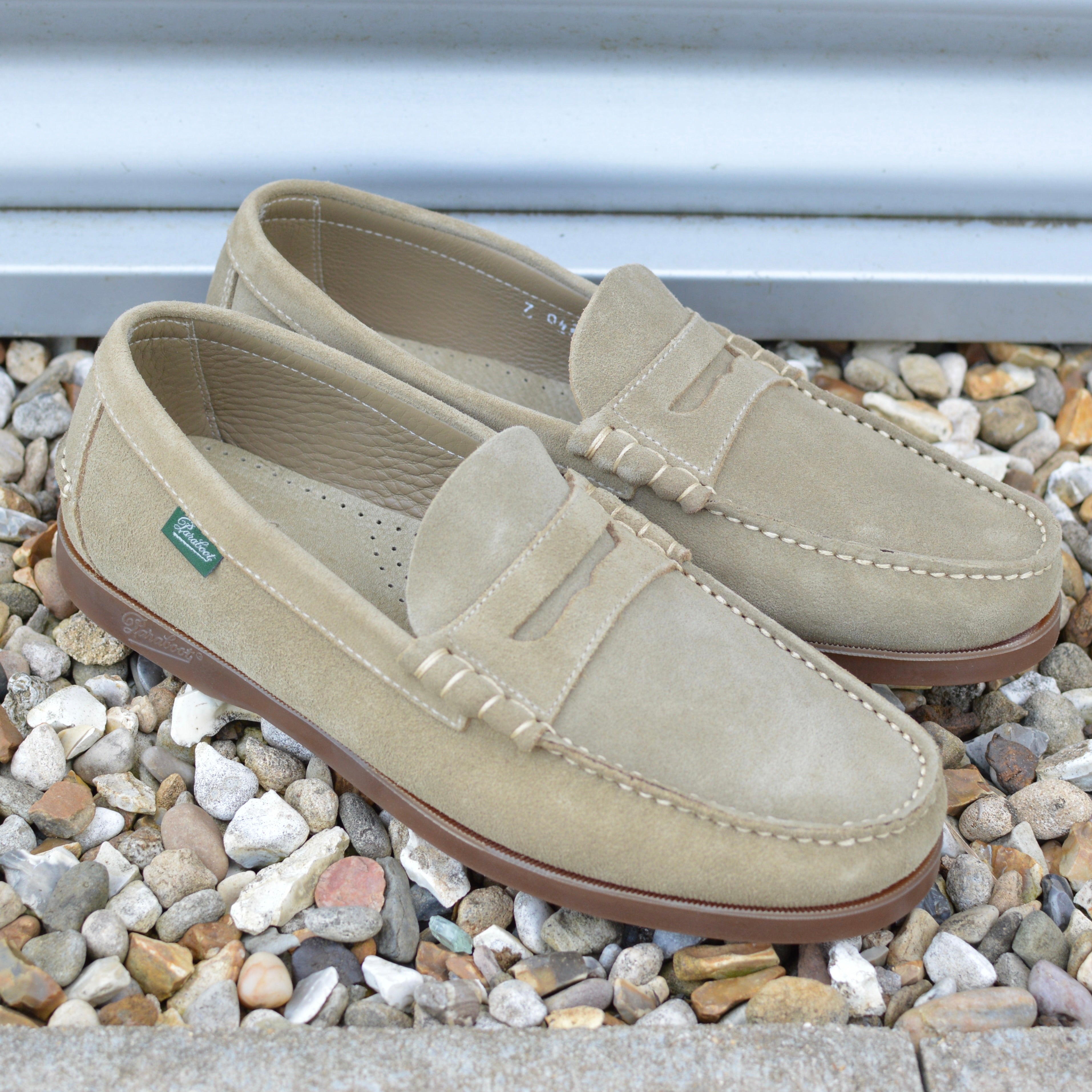 Pair of beige loafers on a bed of small stones