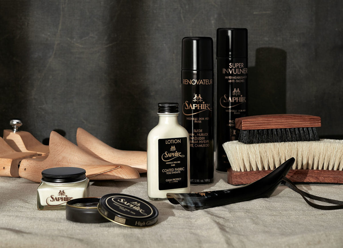 Saphir Medaille D'Or shoe polished and cleaners with horsehair shoe brushes, shoehorn and wooden shoetrees on a fabric surface