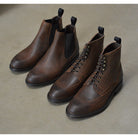 A dark brown lace-up brogue boot with a rubber sole and visible stitching on the upper part.
