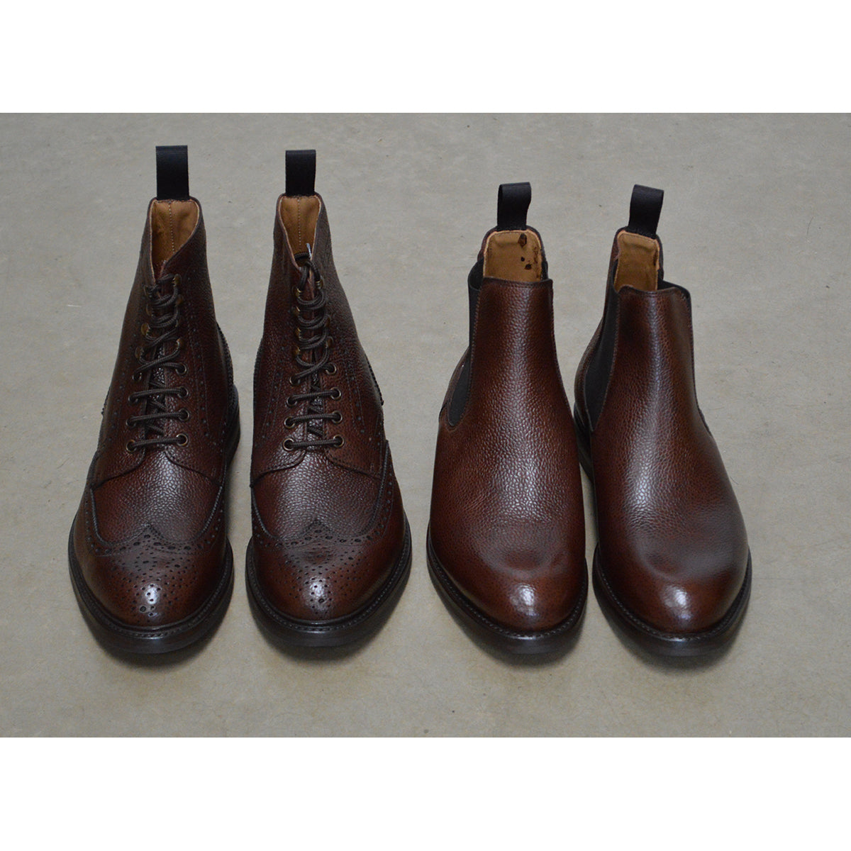 A dark brown grain leather Chelsea boot with a black elastic side panel and a round toe. The boot has a low heel and a goodyear welted dainite rubber sole.