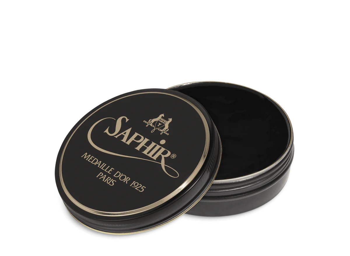 A round tin container of Saphir Medaille D'Or shoe wax polish with black lid and gold lettering.