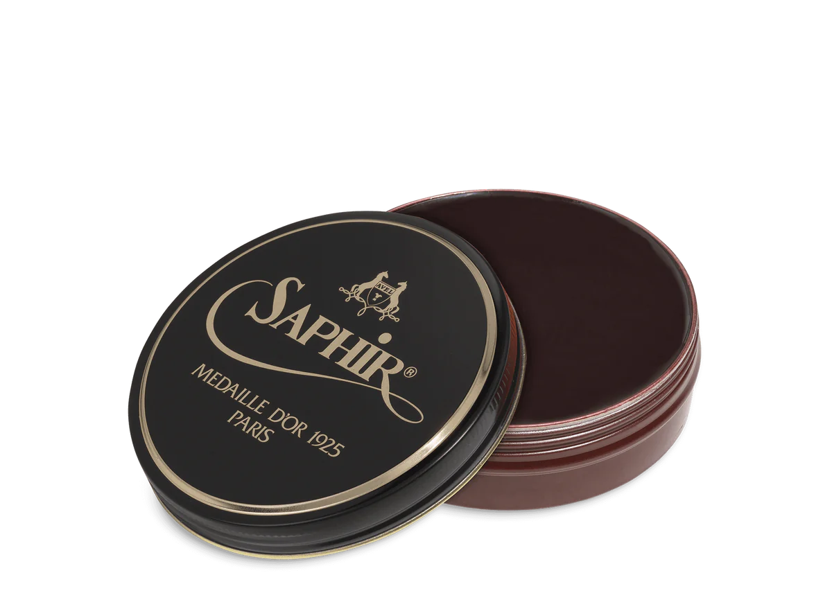 A round tin container of Saphir Medaille D'Or shoe wax polish with black lid and gold lettering.