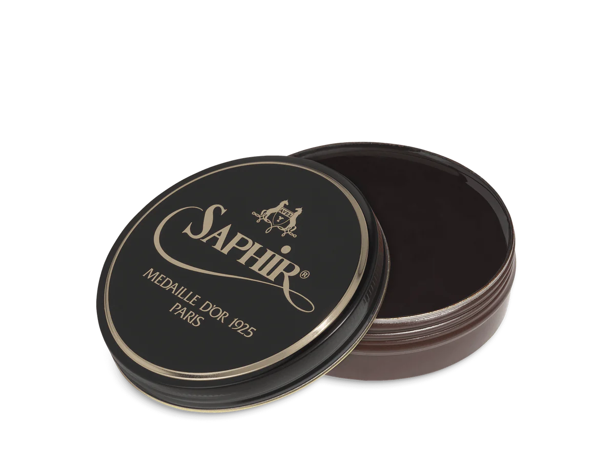 A round tin container of Saphir Medaille D'Or shoe wax polish with black lid and gold lettering.