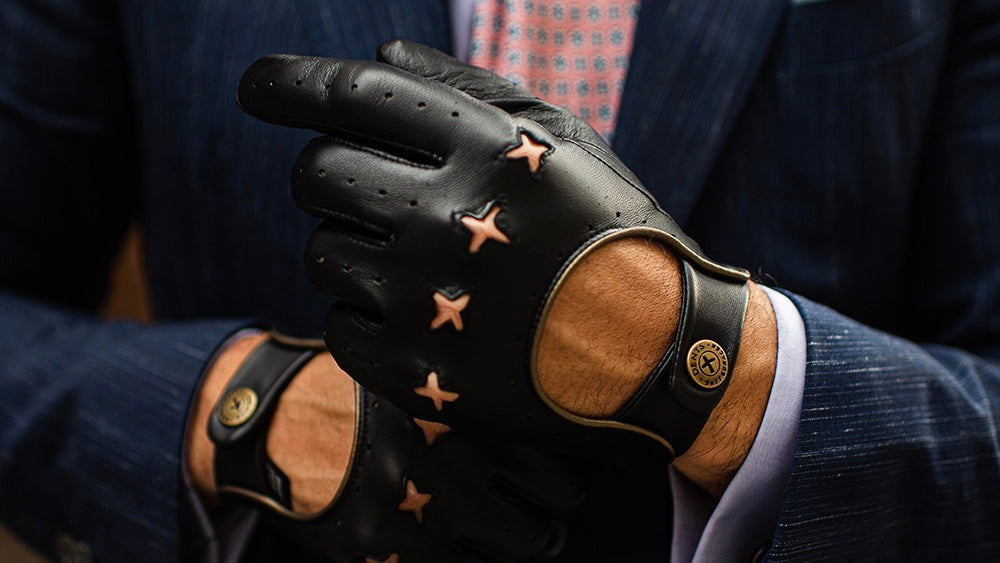 A smart business man wearing Dents leather driving gloves dressed in a suit and tie