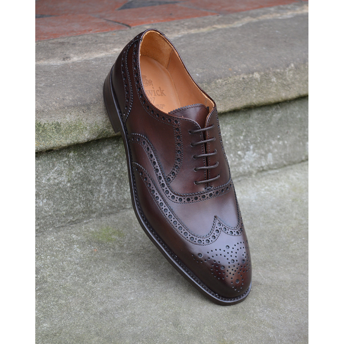 A dark brown Oxford brogue shoe with intricate brogue detailing and a goodyear welted leather sole.